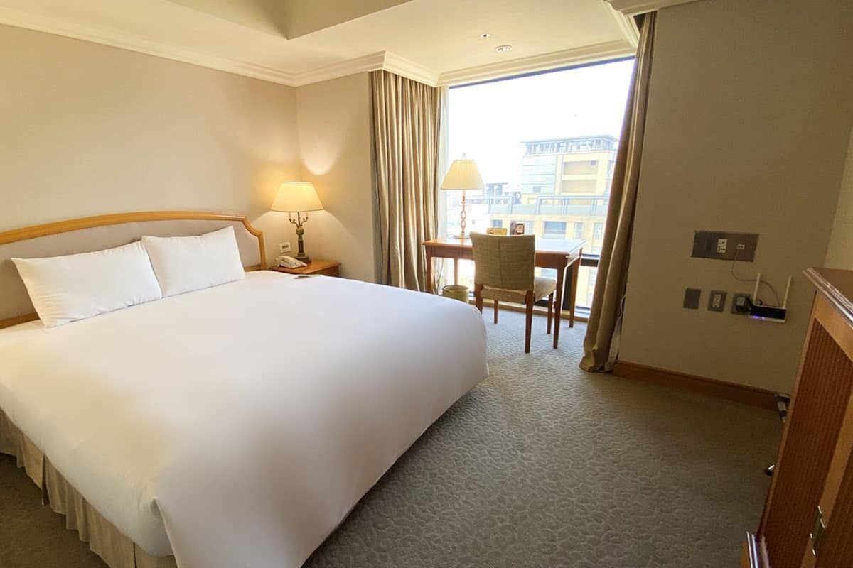 Ett hotellrum med en stor säng, sänglampor, ett skrivbord och en stol.