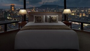 Une chambre d’hôtel avec un grand lit, deux lampes de chevet et une vue sur la ville.