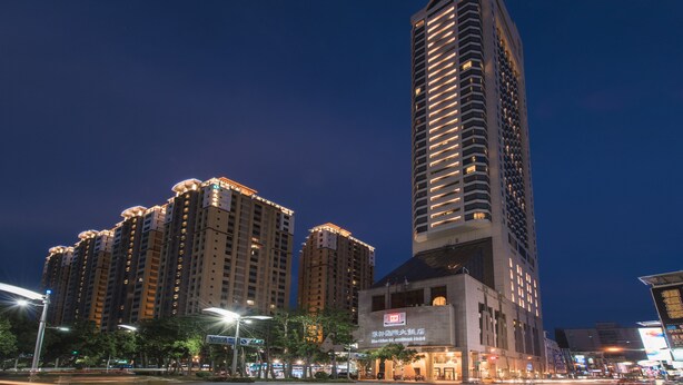 Un hôtel de grande hauteur, avec de nombreux étages, une entrée imposante et entouré d’immeubles urbains.