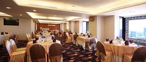A conference room with round tables, chairs, and a carpeted floor.