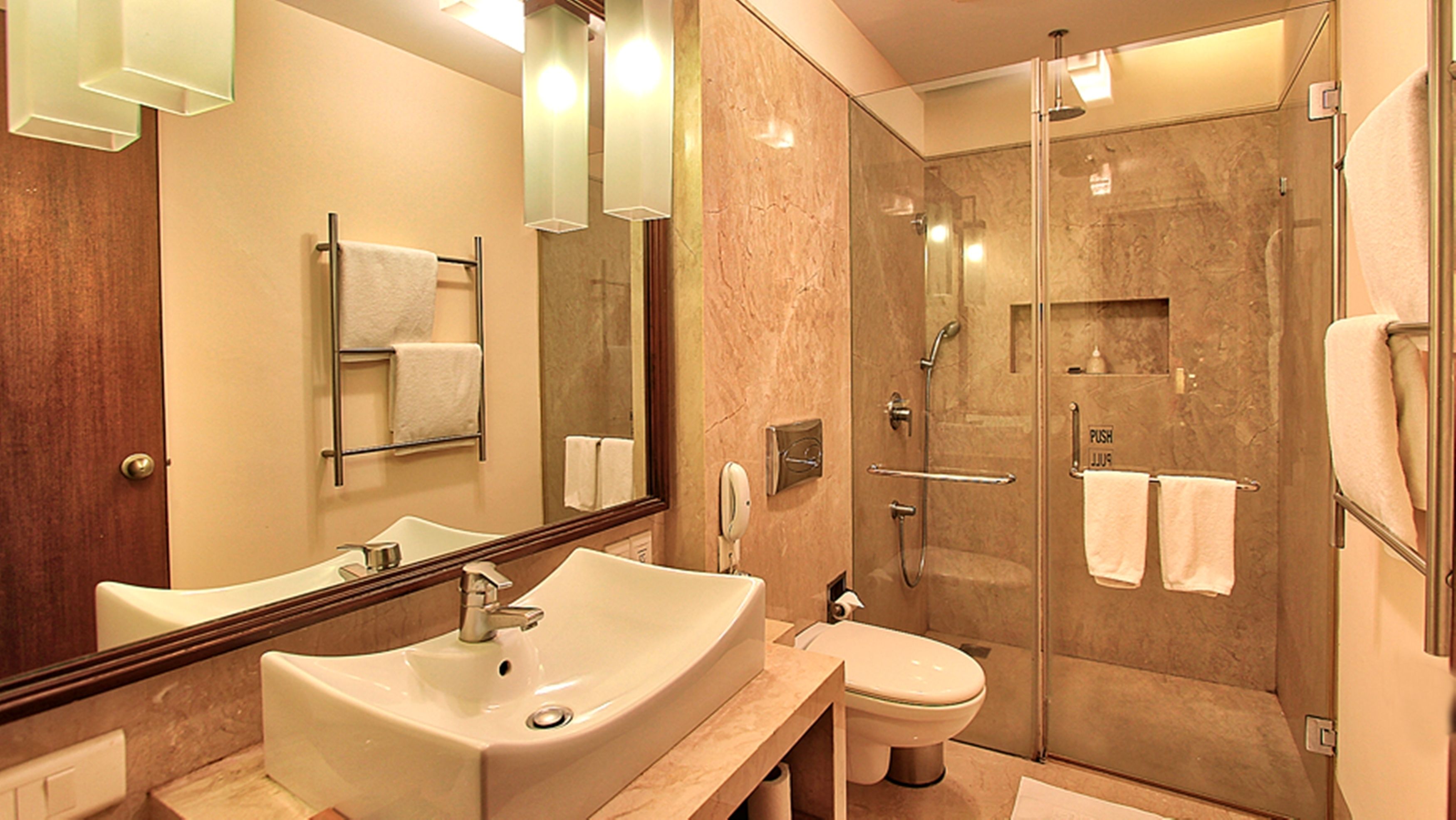A modern bathroom with a large sink, toilet, and glass-enclosed shower.