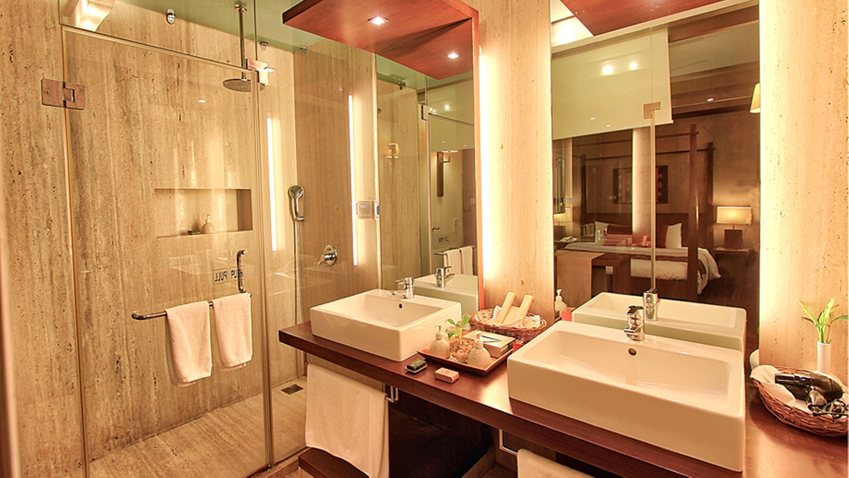 A modern bathroom with two sinks, a glass shower enclosure, and a large mirror reflecting the room.