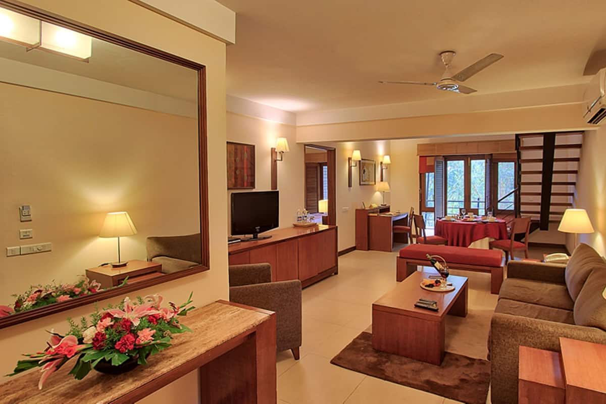 A hotel room with a living area, a dining area, a kitchen, and a large mirror.