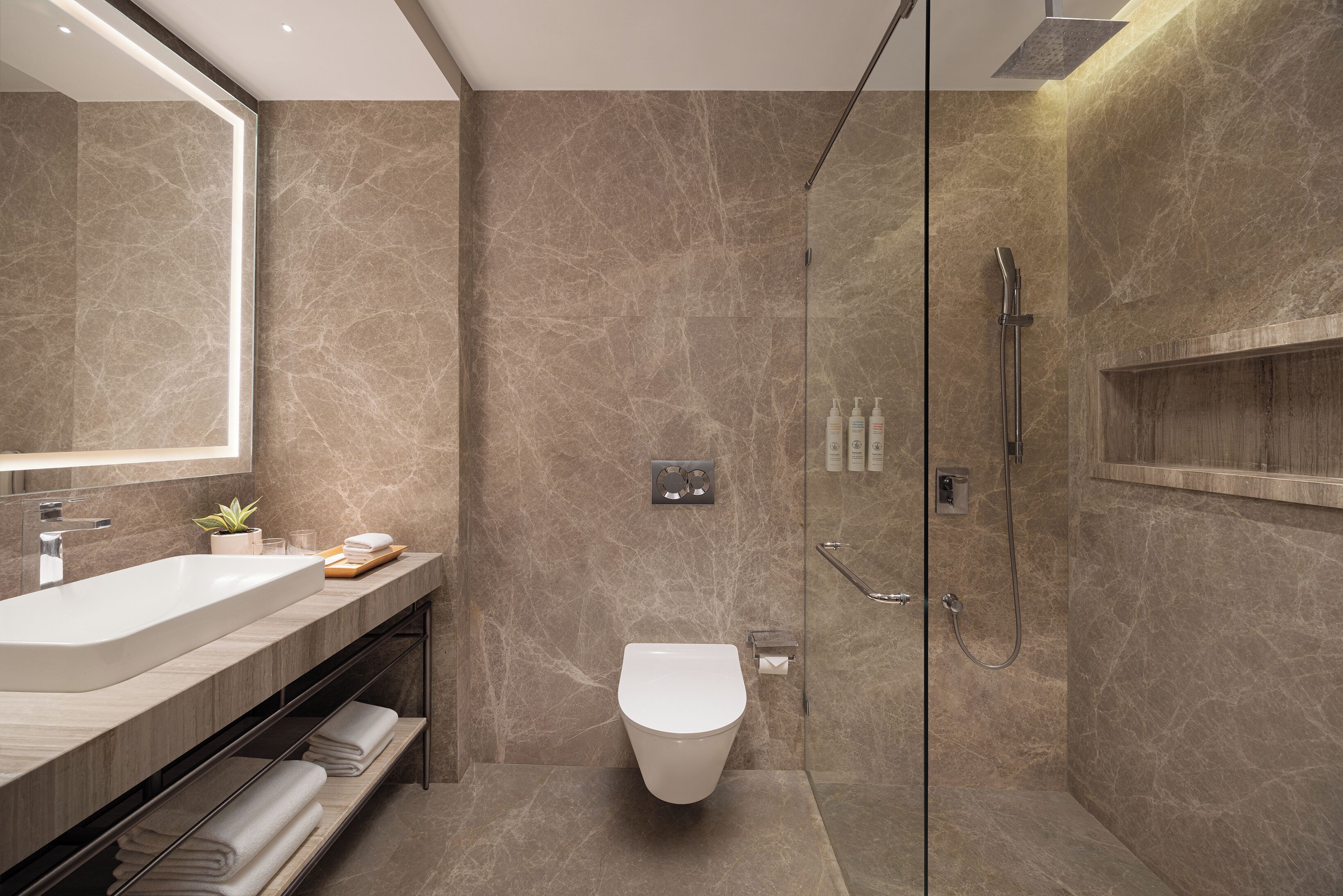 A modern bathroom with a large mirror, a bathtub, a toilet, and a shower area.