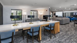 A modern hotel room with a large bed, a desk with a chair, a sofa, and a large window. - Staybridge Suites Madison East by IHG (Madison)