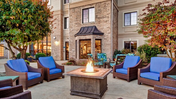 An outdoor patio with wicker furniture and a central fire feature. - Staybridge Suites Madison East by IHG (Madison)
