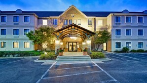 A multi-story hotel with a central entrance, a covered walkway, and a parking lot. - Staybridge Suites Madison East by IHG (Madison)