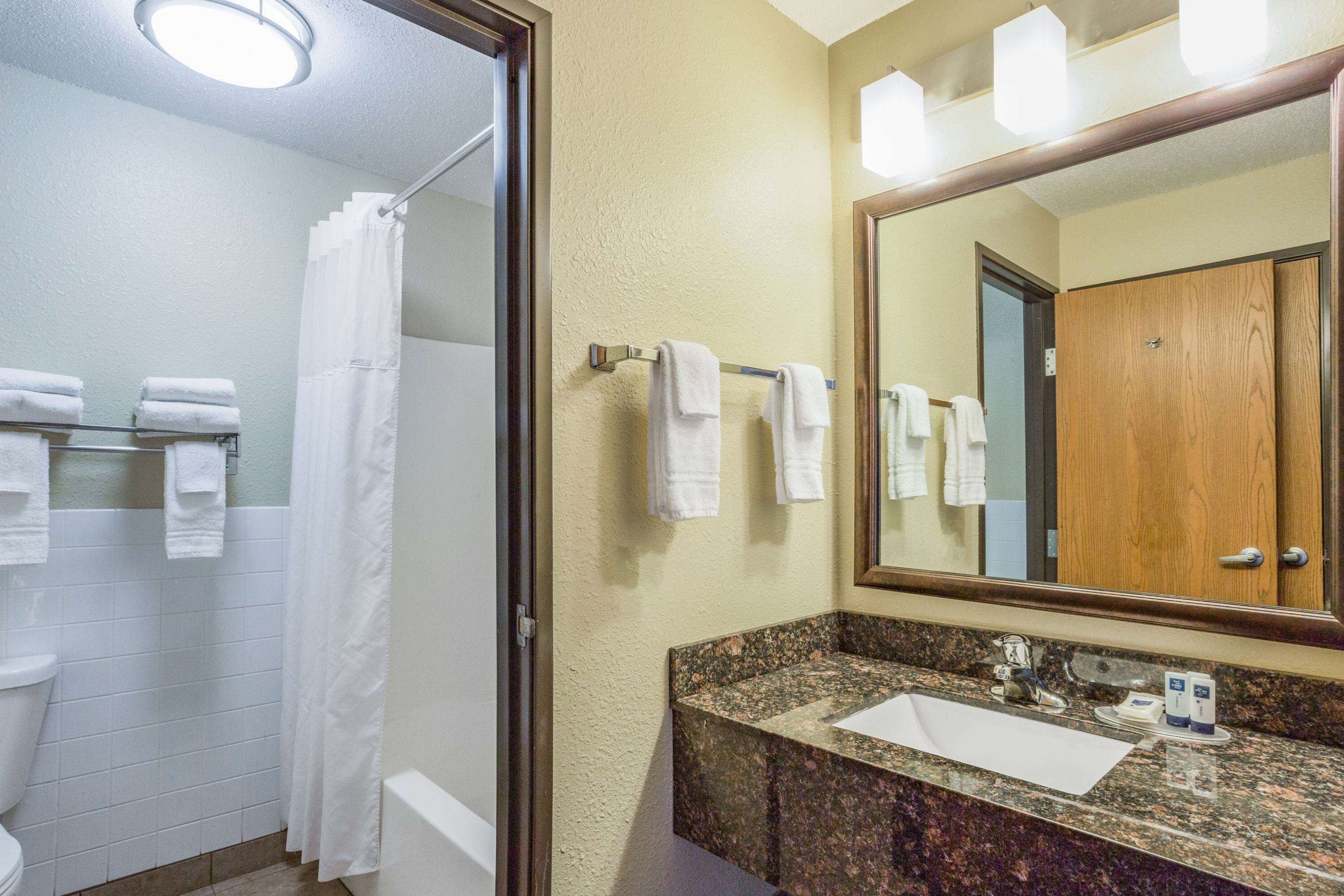 A bathroom with a sink, mirror, and towel rack.