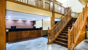 A hotel lobby with a reception desk, a staircase, and a tiled floor. - AmericInn by Wyndham Menomonie (Menomonie)
