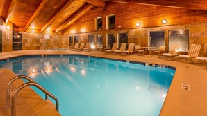 An indoor swimming pool with a wooden ceiling, lounge chairs, and a tiled wall. - Best Western Plus Sidney Lodge (Sidney)
