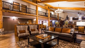 A spacious lobby with a high ceiling, wooden beams, a grand staircase, and a chess table. - Best Western Plus Sidney Lodge (Sidney)