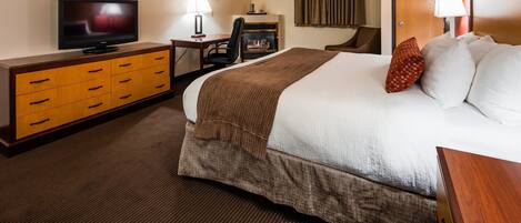 Une chambre d’hôtel avec un lit, une télévision, un bureau et une cheminée.