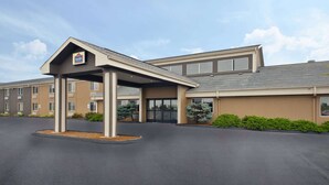 Un hotel con entrada cubierta, varias ventanas y un estacionamiento.