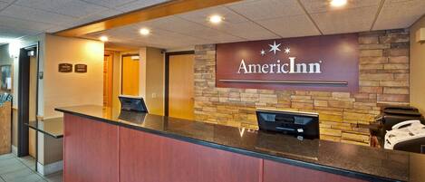 A reception desk with a stone wall backdrop and a sign reading "American Inn".