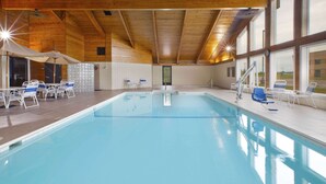 Una piscina interior con techo de madera, paredes de azulejos y vistas al exterior.