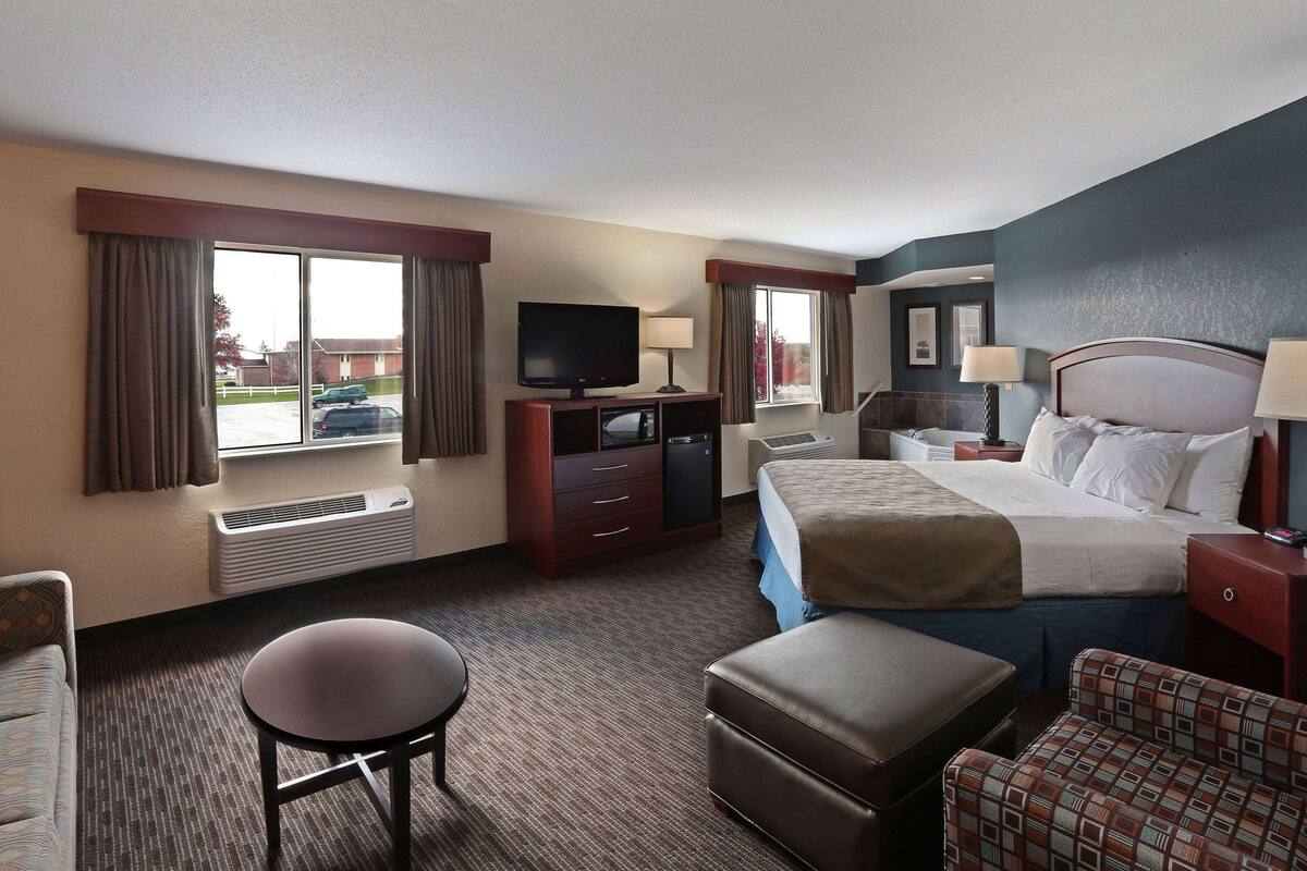 Une chambre d’hôtel équipée d’un lit, d’une télévision, d’un bureau, d’une chaise et d’une fenêtre avec des rideaux.