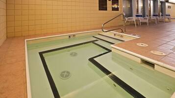 A swimming pool with clear lanes, a diving board, and lounge chairs.