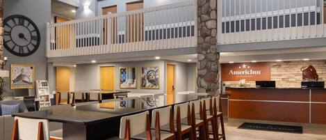 A spacious lobby with a long reception desk, multiple seating areas, and a clock on the wall.