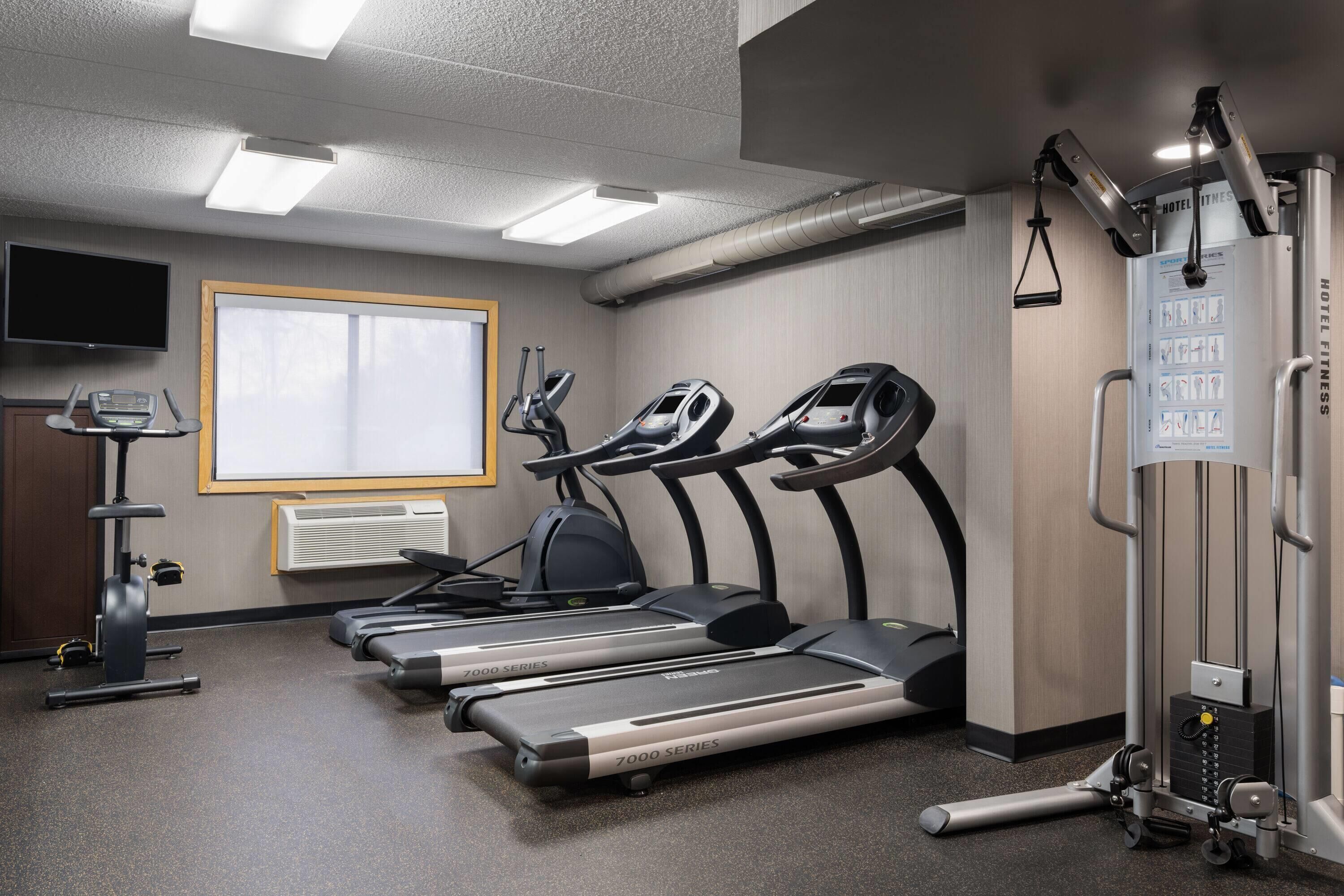 Centro de fitness do hotel com esteiras, elípticos e máquina de pesos.