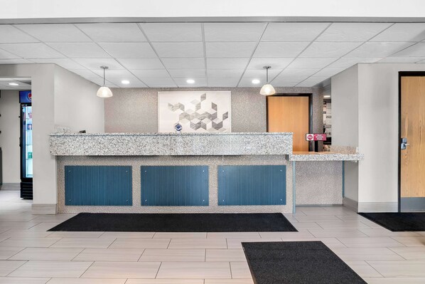 A reception area with a granite counter, blue paneling, a large abstract artwork, and a black rug.