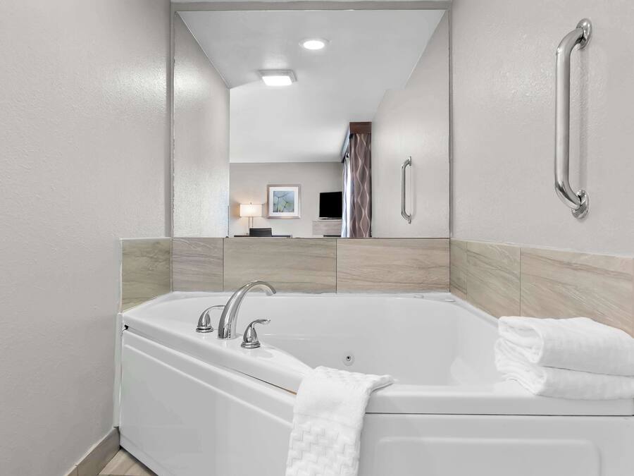 Un baño moderno con una bañera grande, un pasamanos, un espejo y un cuadro enmarcado en la pared.