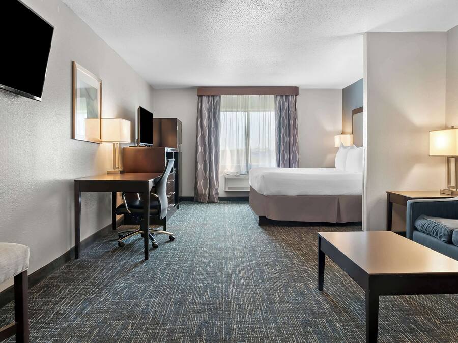 Een hotelkamer met een bed, een bureau met stoel, een televisie, een bank en een lamp.