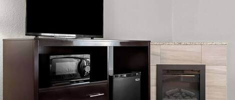 Un buffet en bois foncé, sur lequel sont posés un téléviseur à écran plat, un four à micro-ondes et un réfrigérateur.