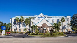 Un hotel grande con un llamativo letrero de 'Baymont Inn & Suites', que presenta un diseño arquitectónico moderno con techo azul y varios pisos.