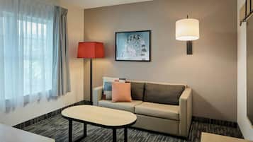 A hotel room with a sofa, a table, a lamp, and a framed picture on the wall.
