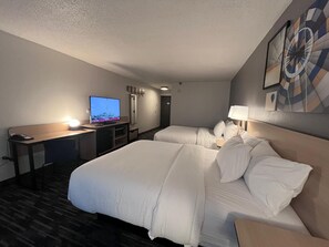 A hotel room with a large bed, a desk with a computer, a TV, and a wall-mounted artwork. - City Express by Marriott Louisville Southeast (Louisville)