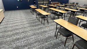 A conference room with multiple tables and chairs, a carpeted floor, and a dark blue wall with a door and a small artwork. - City Express by Marriott Louisville Southeast (Louisville)