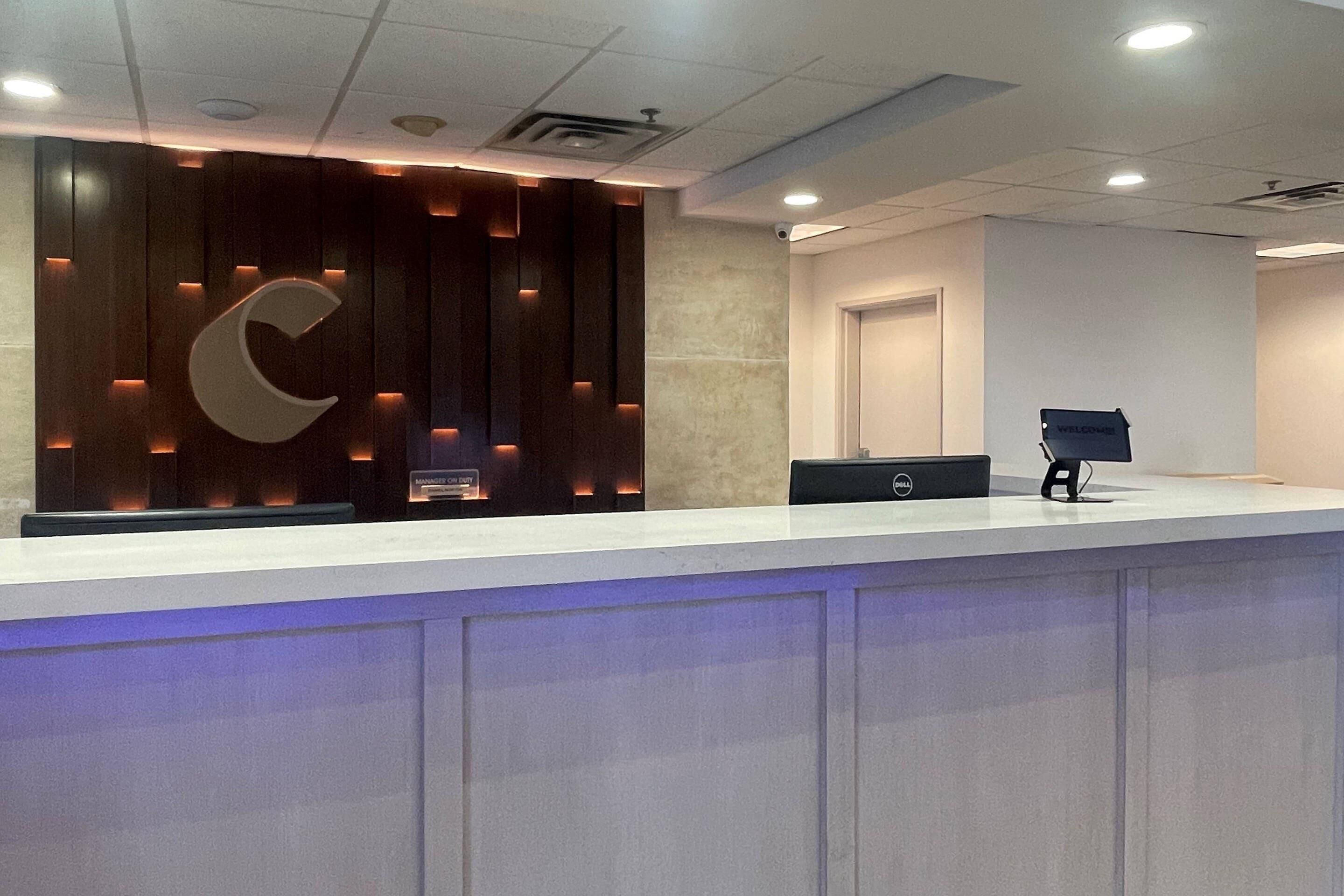 A reception desk with a modern design, a large illuminated letter, and a Dell computer on the counter.