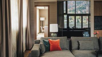 Una sala de estar moderna con un sofá modular, una lámpara y vistas a un lago a través de amplios ventanales.