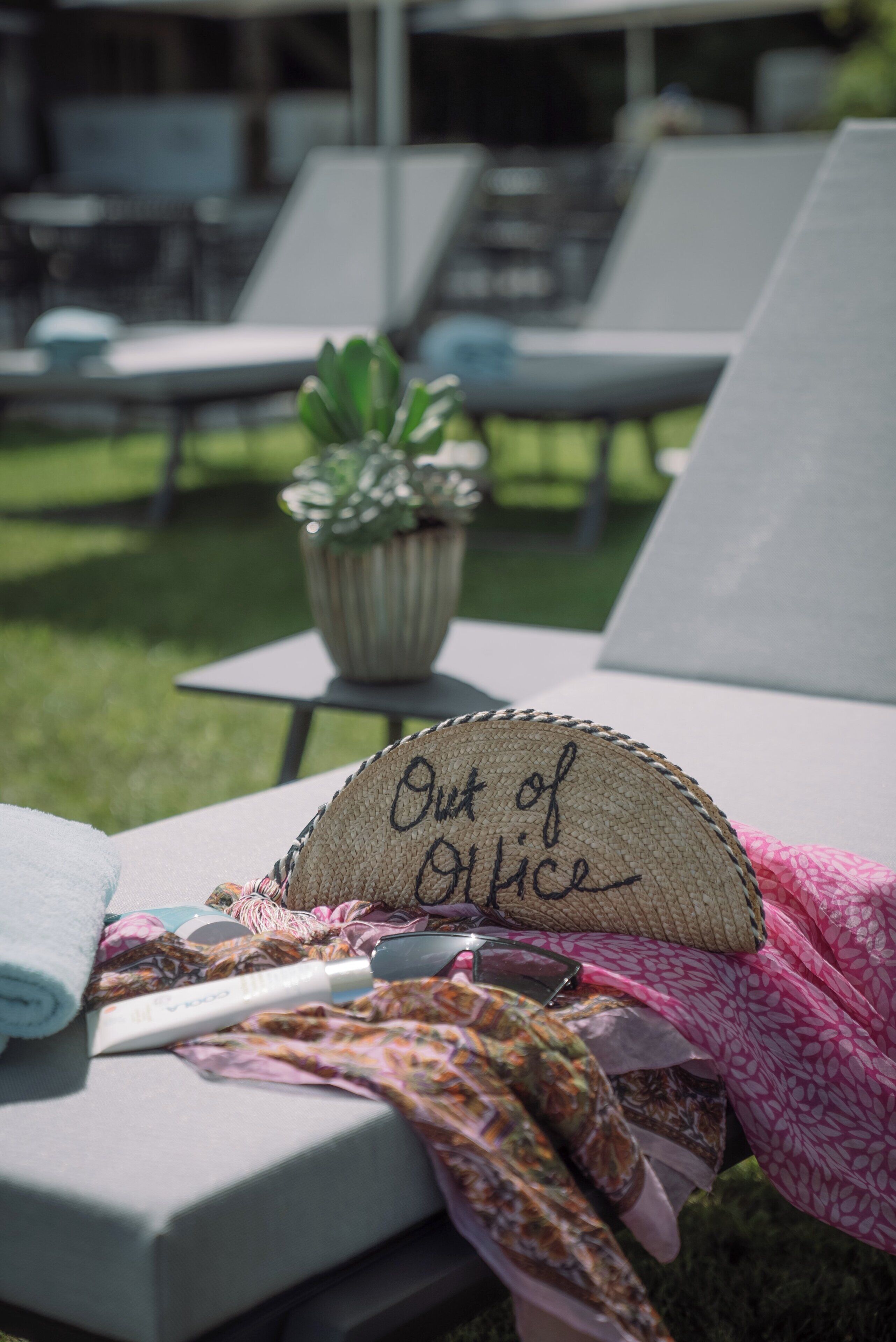 A lounge area with a sign reading "Out of Office," a potted plant, and a towel on a chair.