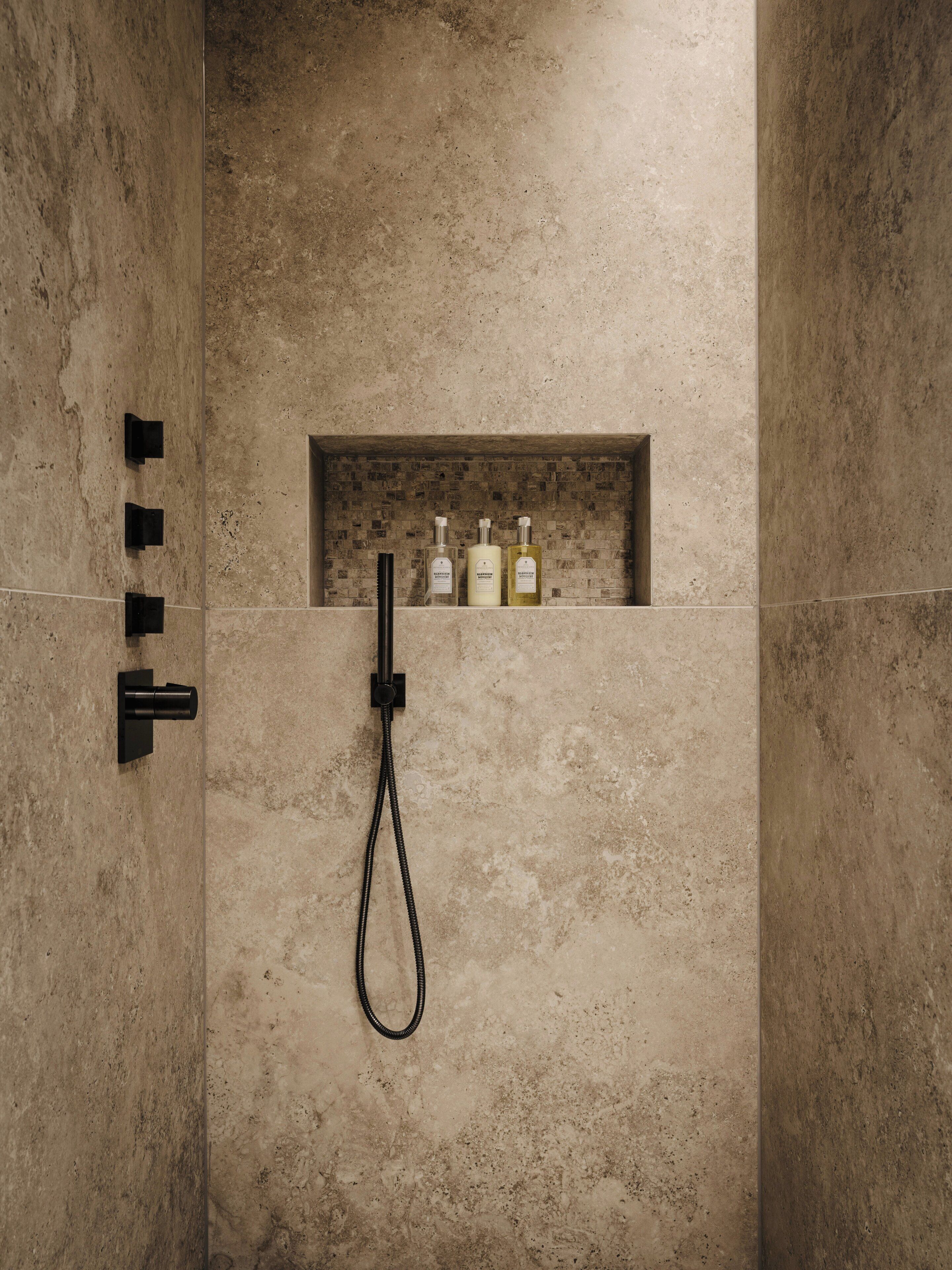 A shower with a handheld showerhead and a wall-mounted control.