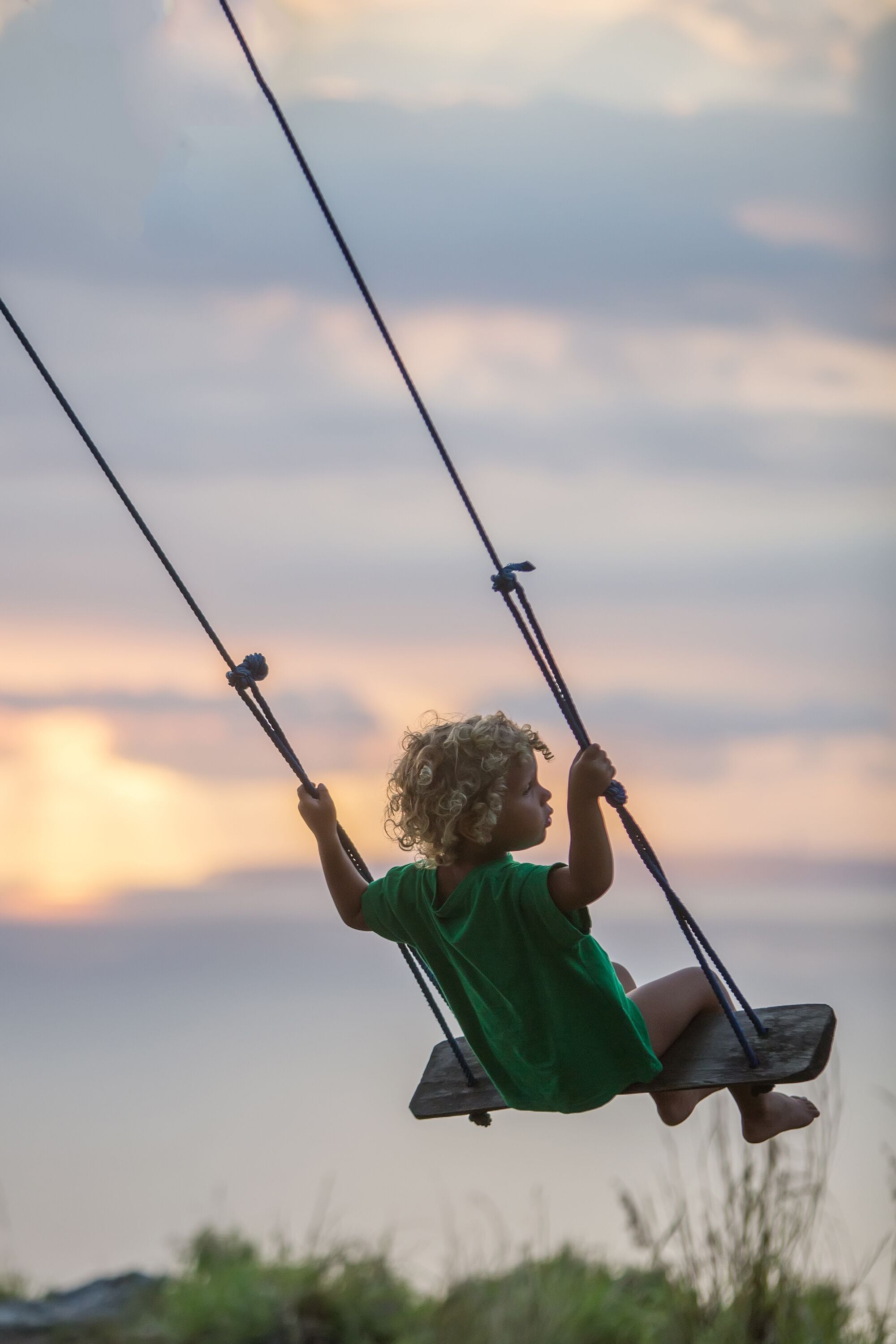 A child on a swing with a sunset in the background.