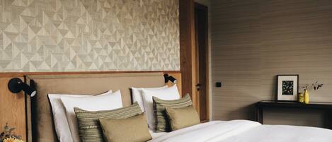 A neatly made bed with pillows, a bedside table with a vase, and a wall with a geometric pattern.
