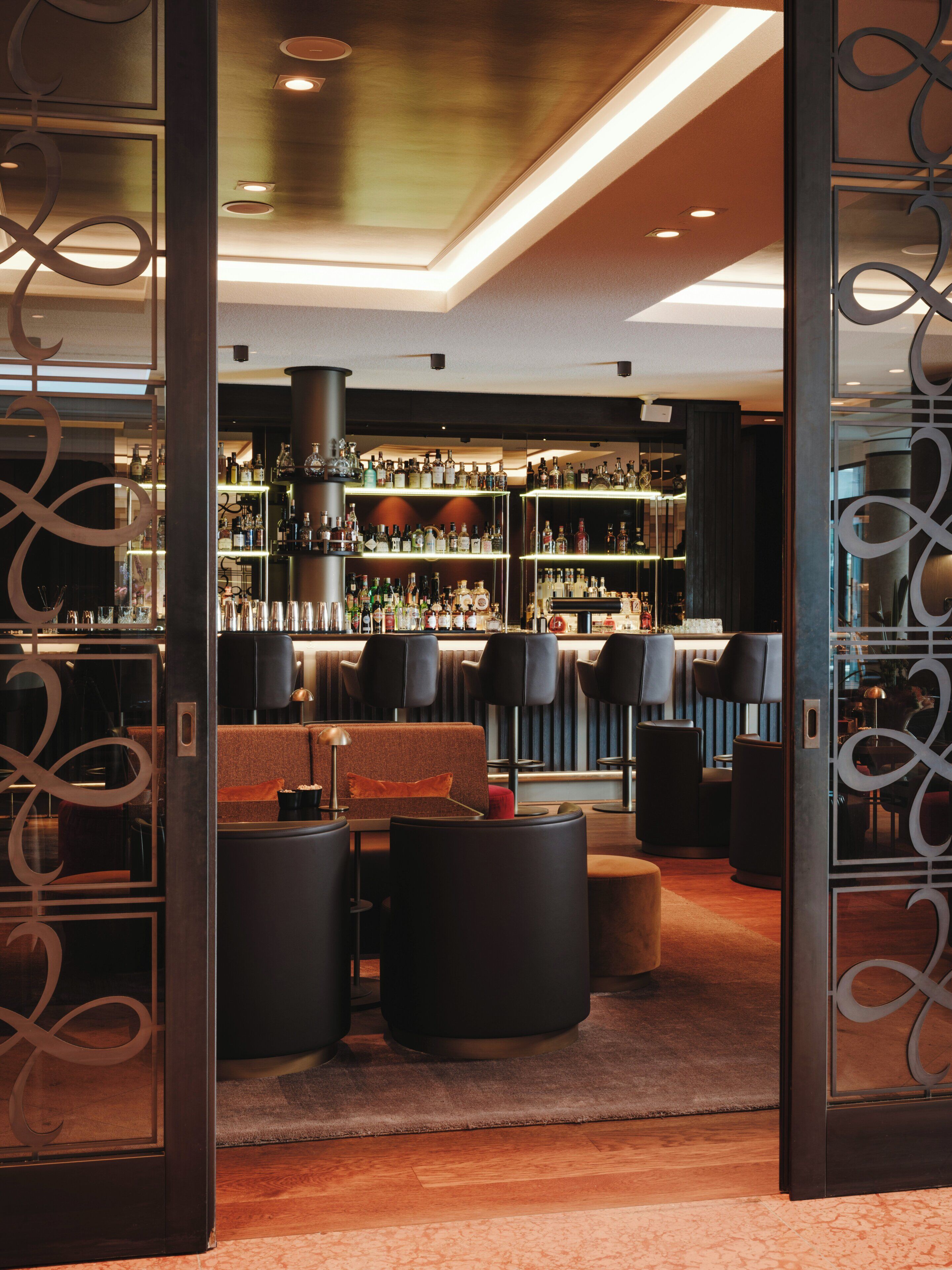 A bar area with seating, a bar counter, and shelves of bottles.