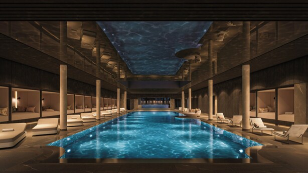 Una piscina interior moderna con techo transparente, sillones de descanso y una zona de estar central.
