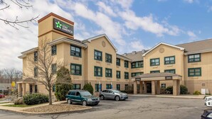 Un hôtel avec une enseigne indiquant « extended stay AMERICA », un hall d’entrée et un parking rempli de voitures.