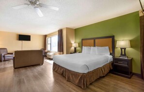 A hotel room with a large bed, a sofa, a TV, and a ceiling fan. - Extended Stay America Suites Somerset Franklin (Somerset)