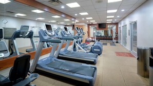 Une salle de sport équipée de tapis de course, de vélos elliptiques et de poids libres.