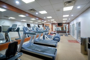 Un gimnasio con cintas de correr, elípticas y pesas sueltas.