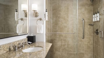 A bathroom with a sink, mirror, towel rack, and shower area.