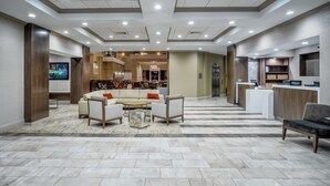 A spacious lobby with a seating area, a reception desk, and a kitchen in the background. - Embassy Suites by Hilton Nashville at Vanderbilt (Nashville)