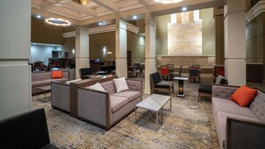 A spacious lobby with a modern design, featuring a mix of seating areas, a reception desk, and a large window providing natural light. - Embassy Suites by Hilton Nashville at Vanderbilt (Nashville)