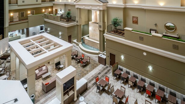A multi-level hotel lobby with a central atrium, multiple dining areas, and a water feature. - Embassy Suites by Hilton Nashville at Vanderbilt (Nashville)