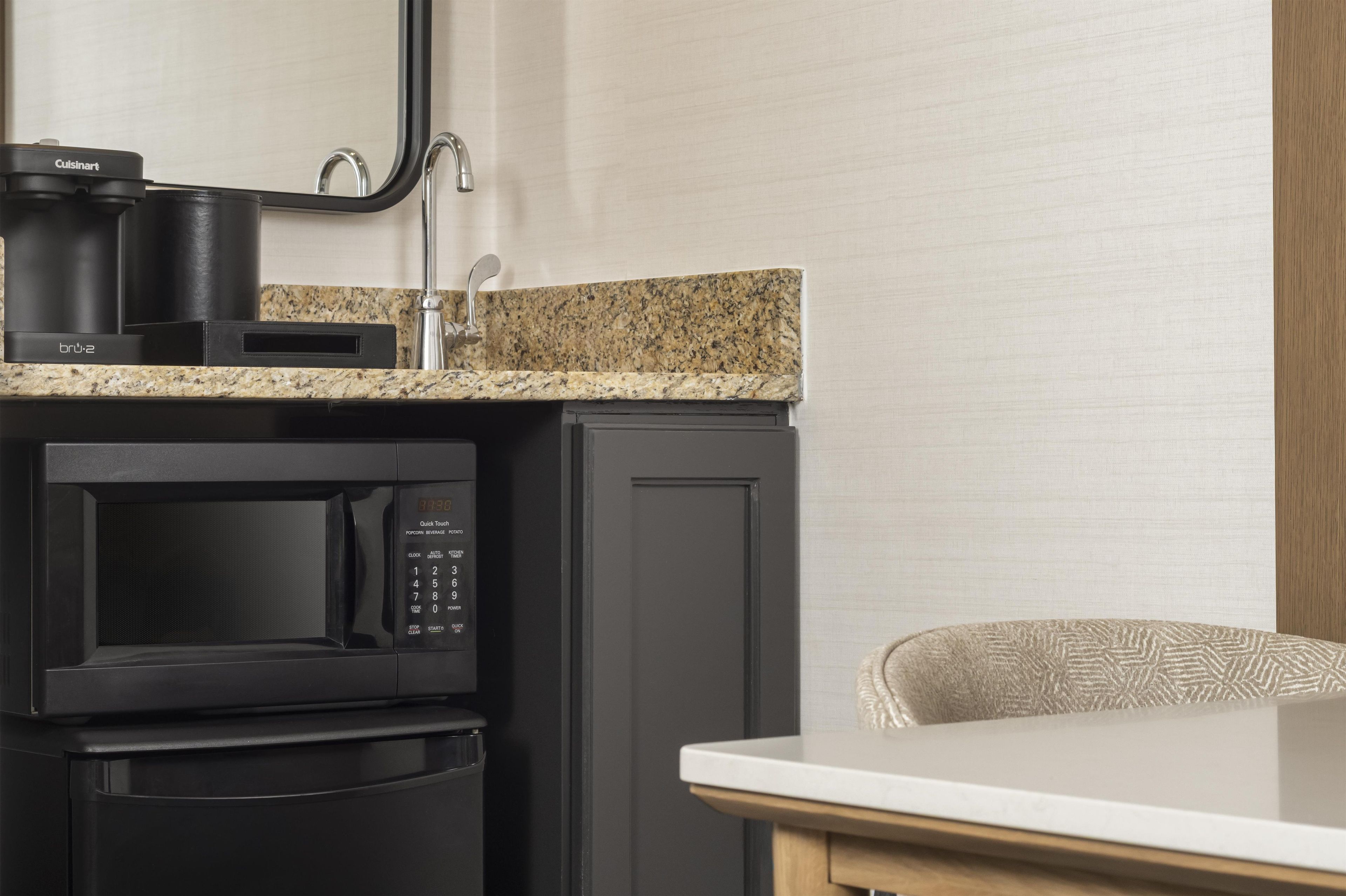 A kitchenette with a microwave, coffee maker, and sink.