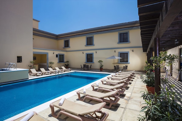 Relax by the serene pool surrounded by lounge chairs and lush greenery.