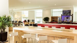 A modern bar area with a long wooden counter, white chairs, and a television screen. - Fiesta Inn Periferico Sur (Mexico City)